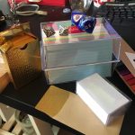 A pack of gold playing cards, a box of index cards, a box of blank business-style cards and envelopes they fit in, two sets of percentile (d%) dice